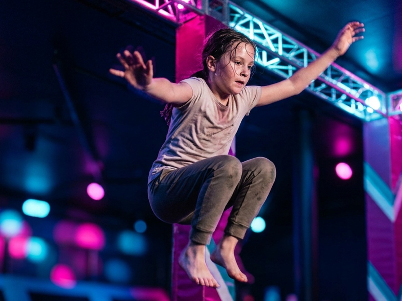 A child airborne between platforms at Tru Ninja